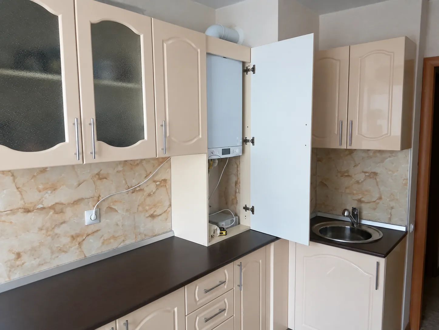 Газовый котёл в кухонном шкафу с открытой дверью